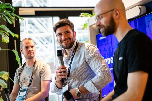 Panel speaker smiling with a microphone between two other speakers