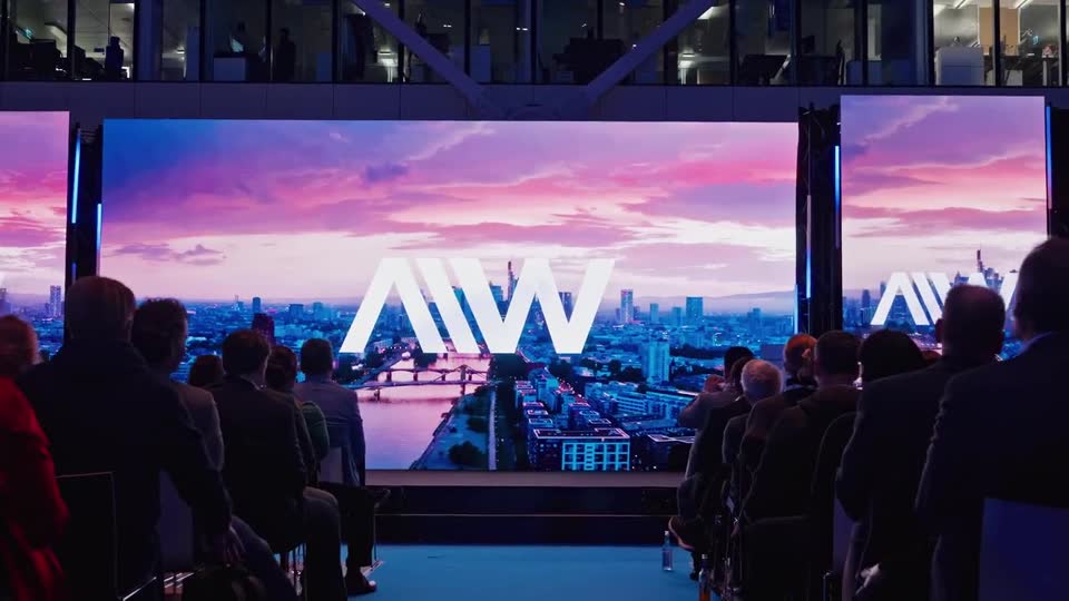 Audience in the dark in front of a giant stage screen at AI Week Frankfurt