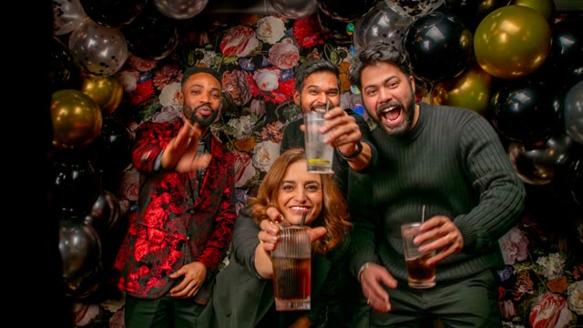 Vier Kollegen lachen vor einer Wand aus Ballons und Blumen