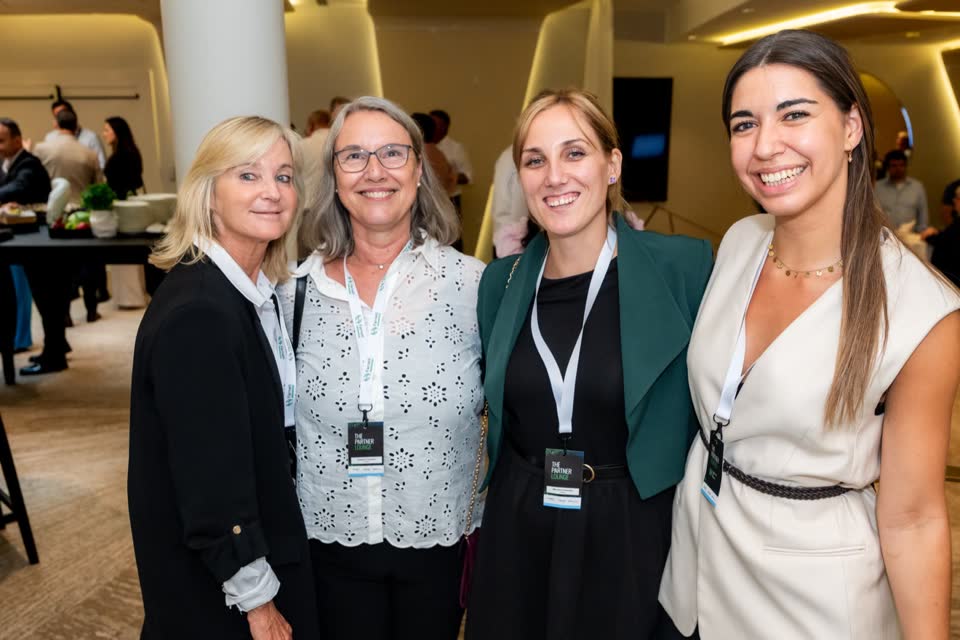 Four conference guests with lanyards smiling arm in arm