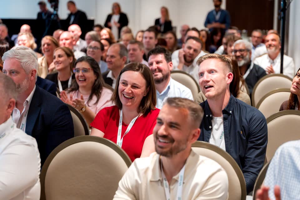 Publikum lacht in den Stuhlreihen einer Konferenz
