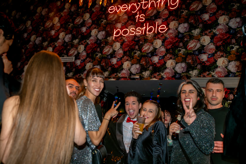 Eine Gruppe posiert unter einem Neonschild mit dem Satz everything is possible